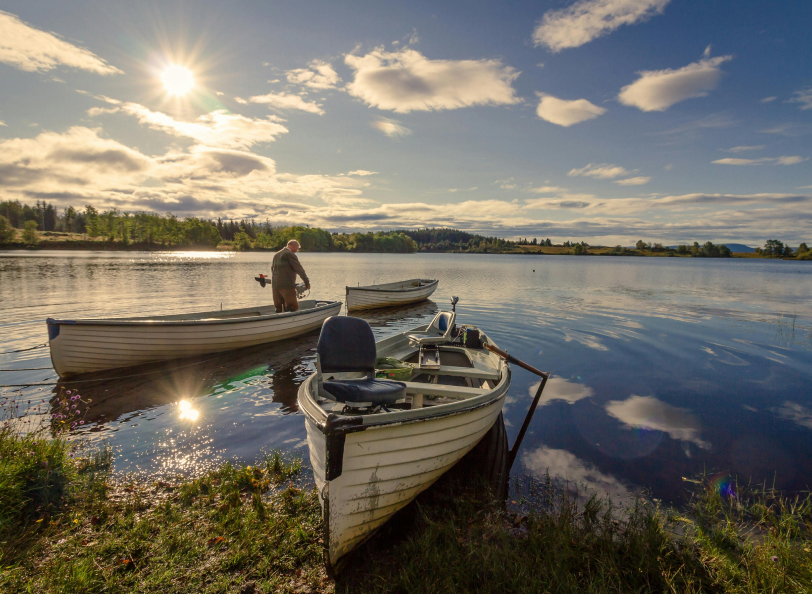 Two parked fishing boats near te show and the lake reflecting the sky and clouds