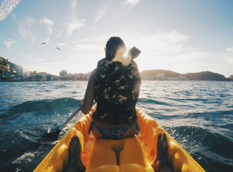 A close up of the back of a woman in a life vest sitting on kayack