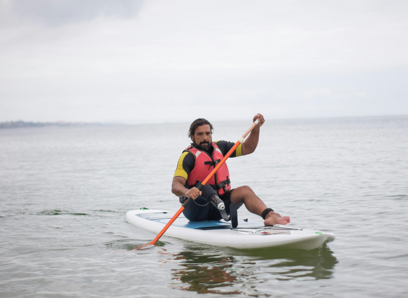 A man with prostetic leg paddlig on a stad up kayack
