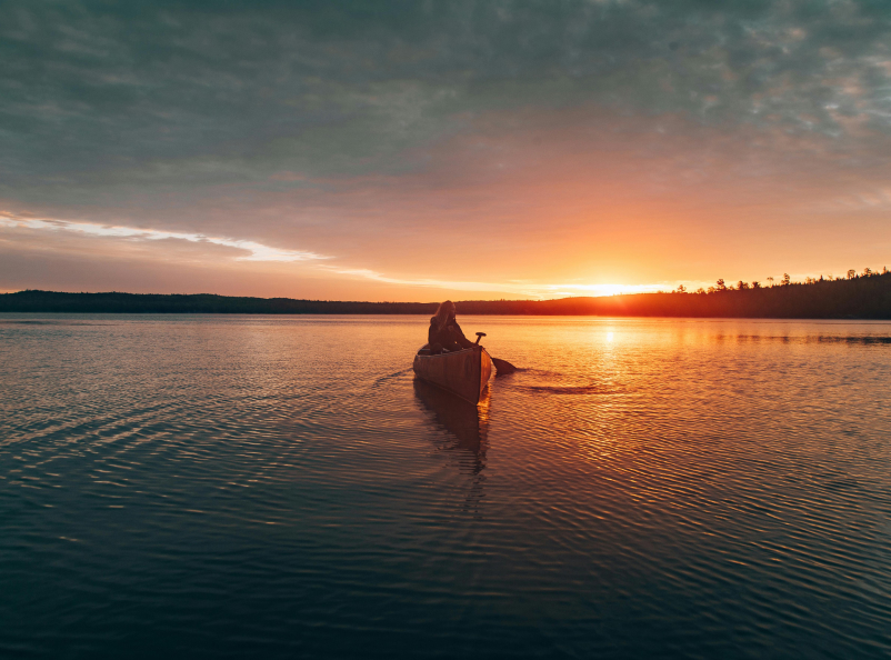 A scene of a boat on a lake at sunset